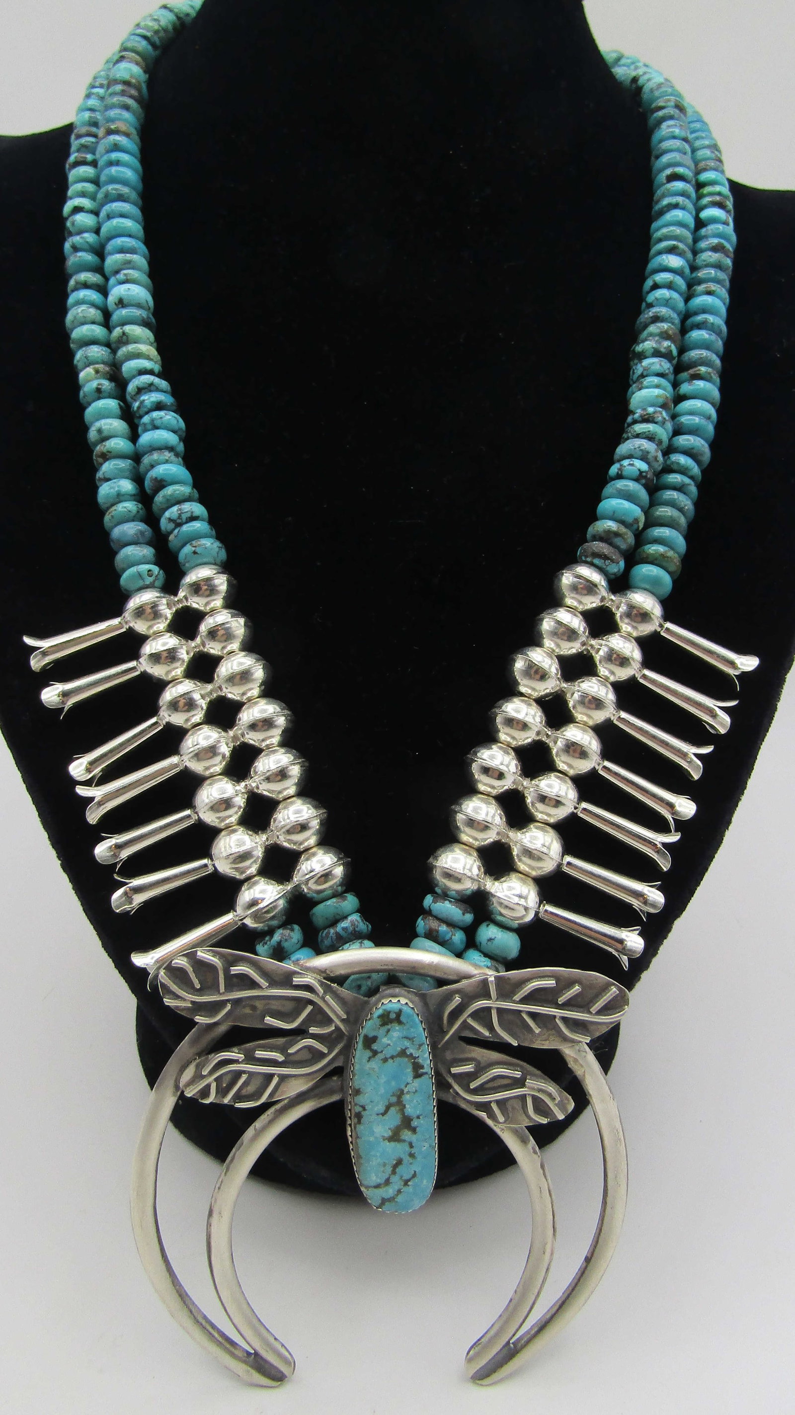 DRAGONFLY TURQUOISE STERLING SILVER NECKLACE 162GR: 10MM TURQUOISE BEADS & MARKED "STERLING" SILVER SQUASH BLOSSOM DRAGONFLY NECKLACE. NATIVE AMERICAN SOUTHWEST NAVAJO INDIAN JEWELRY. MEASURES 25 INCHES LONG PLUS3 INCH NAJA. WEIGHS 163.2 GRAMS. EXCELLE