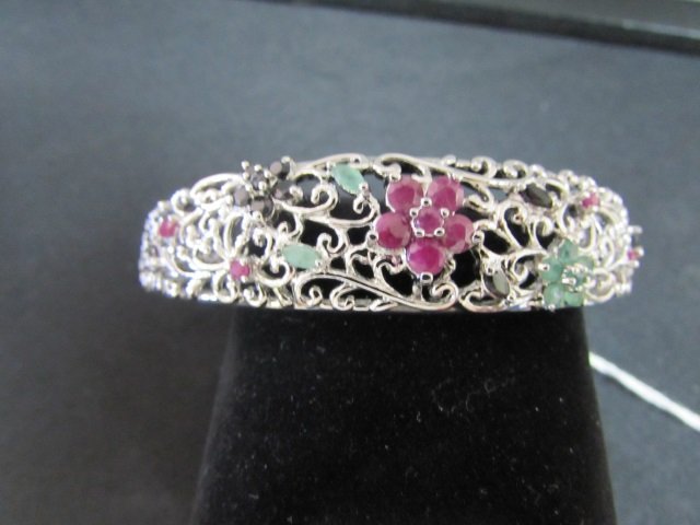 EMERALD RUBY SAPPHIRE BRACELET STERLING SILVER: 3.745 All Genuine Emerald, Ruby and Sapphire Gemstones Mounted in a Sterling Silver Filigree Bangle Bracelet. Large Size will Fit a 7 to 8 inch Wrist. Measures 1/2 inch wide in front , by 2 3/4 inches