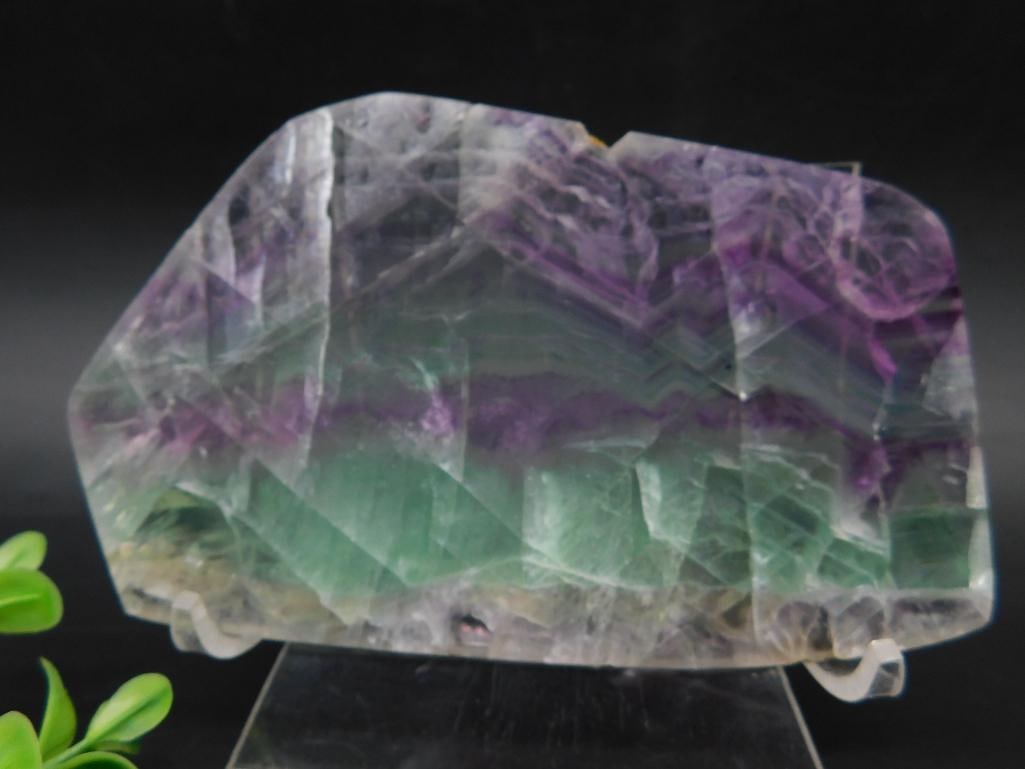 Fluorite Crystal Display Specimen: This lot features a natural fluorite crystal specimen. The piece showcases beautiful shades of purple and green with banded patterns. It is presented on a clear stand and is suitable for display. The 