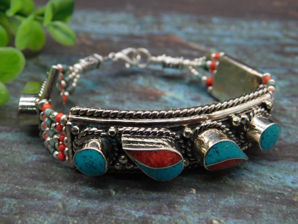 Beaded Bracelet with Turquoise and Red Accents: This intricate bracelet features turquoise and red stone inlays complemented by detailed silverwork. The design includes unique beadwork and metal accents, with a secure clasp for closure. Ideal for c