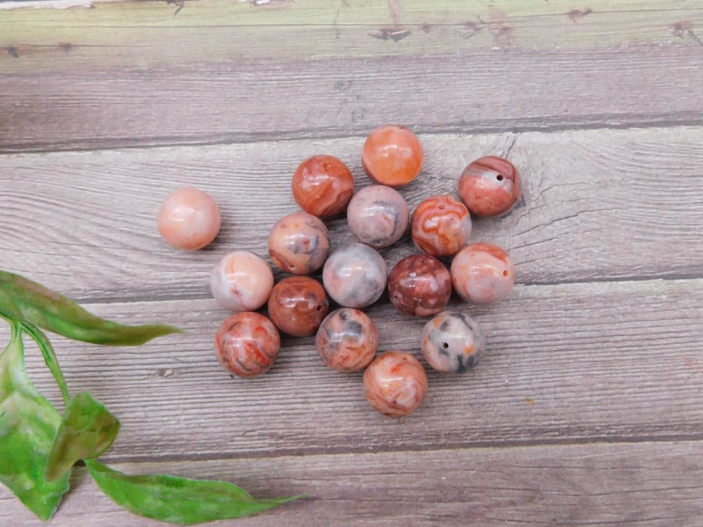 Group of Red Spherical Beads with Natural Veining: This lot consists of a group of spherical beads, primarily red in color with naturally occurring veining and patterns. Ideal for crafting or jewelry-making purposes, each bead features a drilled hole 