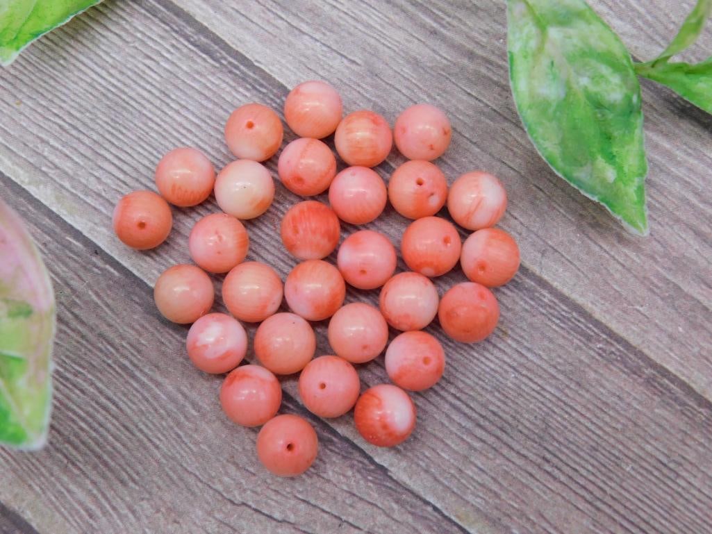 Lot of Pink Coral Beads for Jewelry Making: This lot includes a collection of pink coral beads, ideal for crafting or jewelry projects. Each bead features a round shape with a drill hole for stringing. The beads are natural in appearance with i