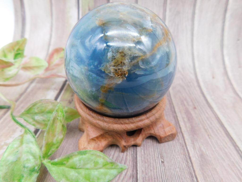 Polished Blue Stone Sphere: Polished stone sphere featuring shades of blue with natural patterns and inclusions. Weighs approximately 323 grams. Ideal for collectors or display purposes. Ruler shown for scale.