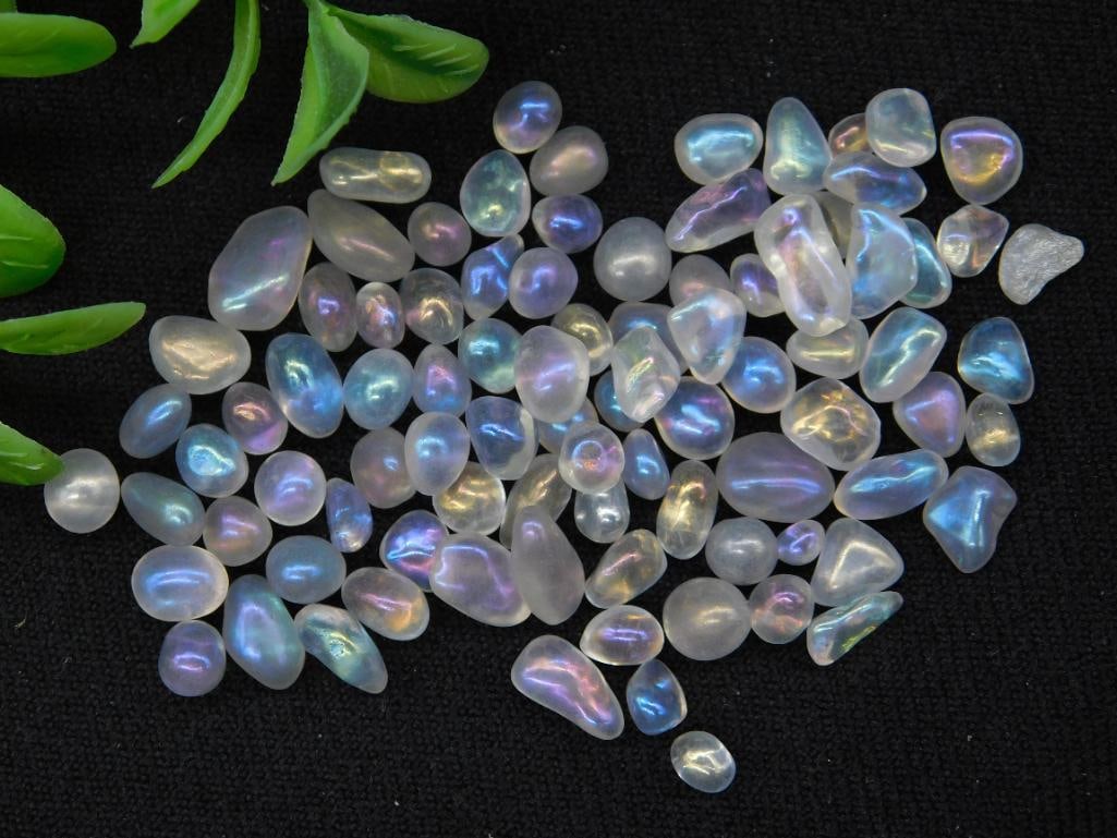 14 Grams of Polished Moonstone Gemstones: Lot of polished moonstone gemstones, totaling 14 grams. The stones display a variety of shapes and sizes with a translucent finish and iridescent hues. Ideal for collectors or jewelers. Includes the l
