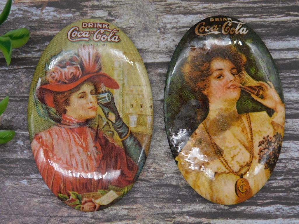 Pair of Coca-Cola Advertising Pocket Mirrors: Pair of Coca-Cola advertising pocket mirrors featuring vintage-themed artwork. One mirror showcases a lady in a red hat, holding a handheld fan, while the other depicts a lady wearing a medallion neck