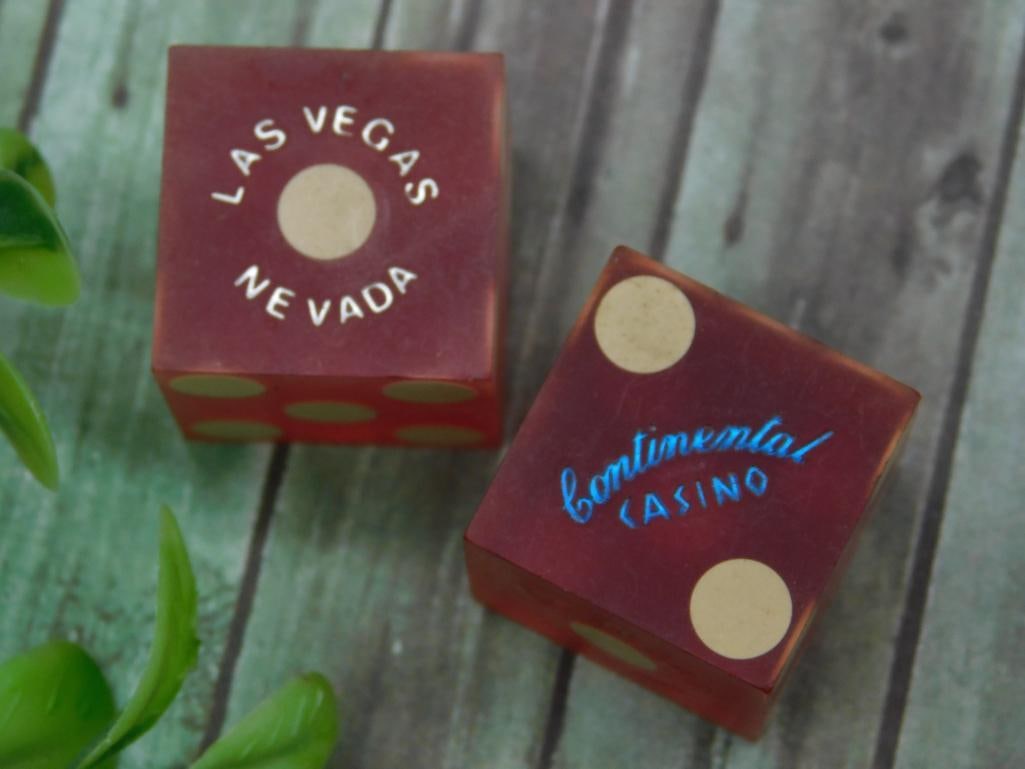Set of Two Las Vegas Continental Casino Dice: A pair of red dice featuring gold dots and inscriptions. One die is labeled 'Las Vegas Nevada,' while the other reads 'Continental Casino.' Great condition with visible markings. Includes accompanying