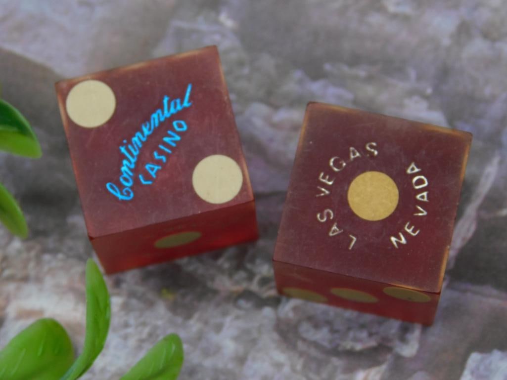 Pair Of Las Vegas Continental Casino Dice: This lot features a vintage pair of dice from the Continental Casino in Las Vegas, Nevada. Both dice have gold pips and feature the casino's name in gold and blue print. A 1948 quarter is shown for sc