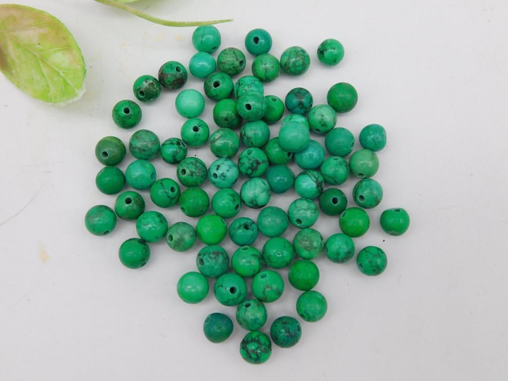 Assorted Polished Green Beads for Jewelry Making: Lot of polished green beads, ideal for crafting and jewelry making. Includes an assortment of spherical beads with drilled holes, suitable for stringing or wirework. Color variations range from light 