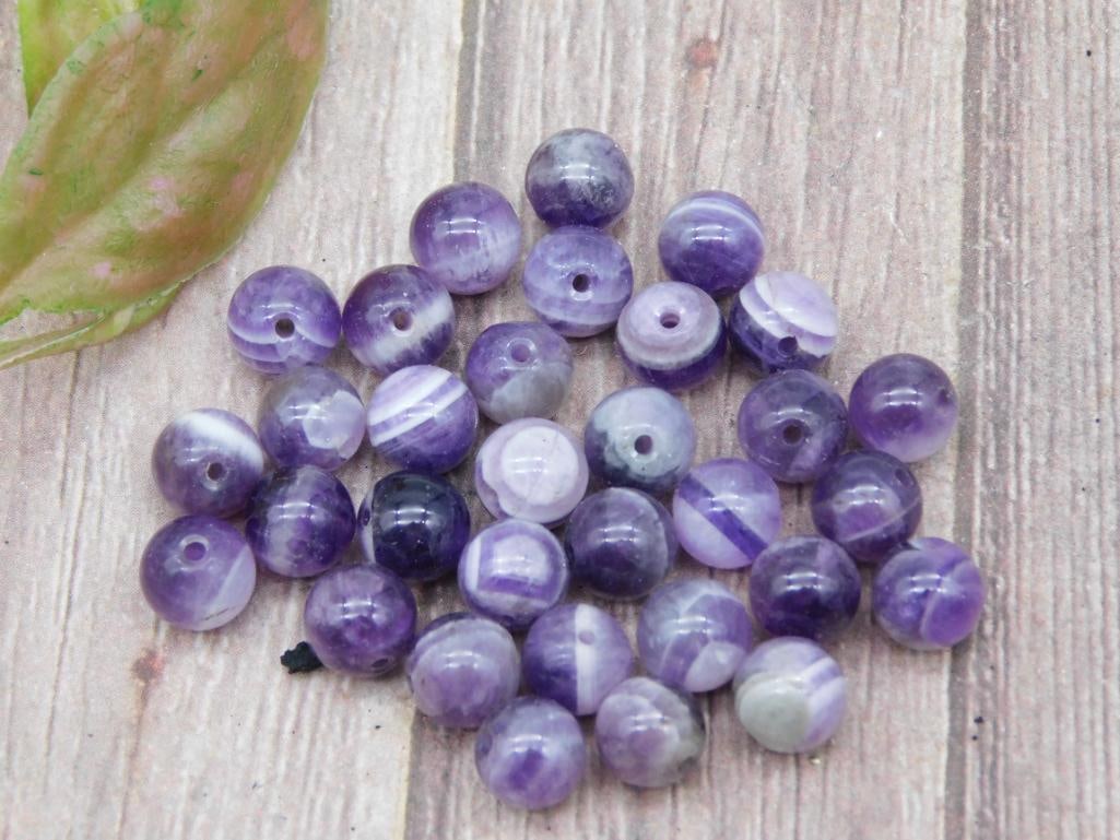 Lot of Purple Agate Stone Beads With Drill Holes: Lot of approximately 30 purple agate stone beads, each featuring natural striations and drill holes for stringing or crafting. Beads are of spherical shape and uniform size, ideal for use in jewelry-m