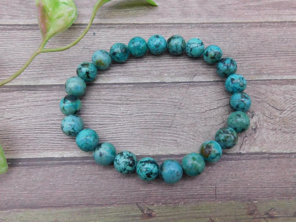 Turquoise Beaded Stretch Bracelet with Round Stones: This lot features a turquoise beaded stretch bracelet comprised of uniformly sized round beads. The natural turquoise stones exhibit variations of blue and green hues with black matrix patterns. The b