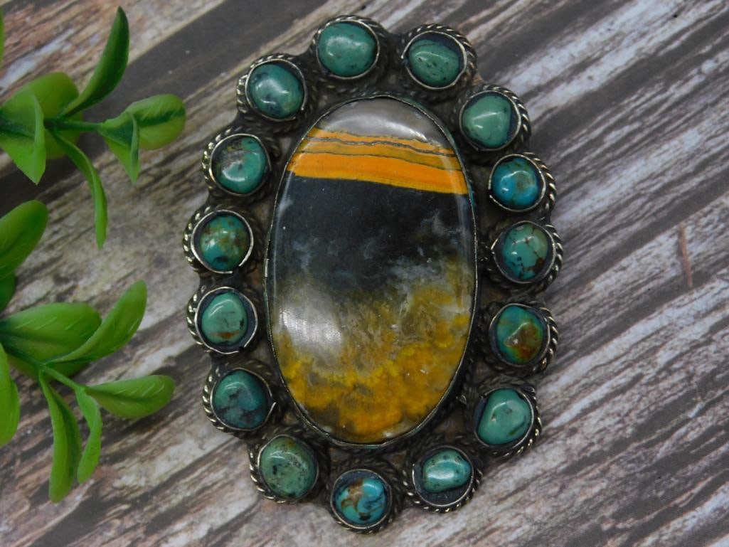 BUMBLEBEE JASPER AND TURQUOISE PENDANT ROCK STONE LAPIDARY SPECIMEN: This silver belt buckle features an intricate ornate design on the reverse side and showcases a large oval multicolored stone inlay at the center. The central stone is surrounded by a ring of smaller 