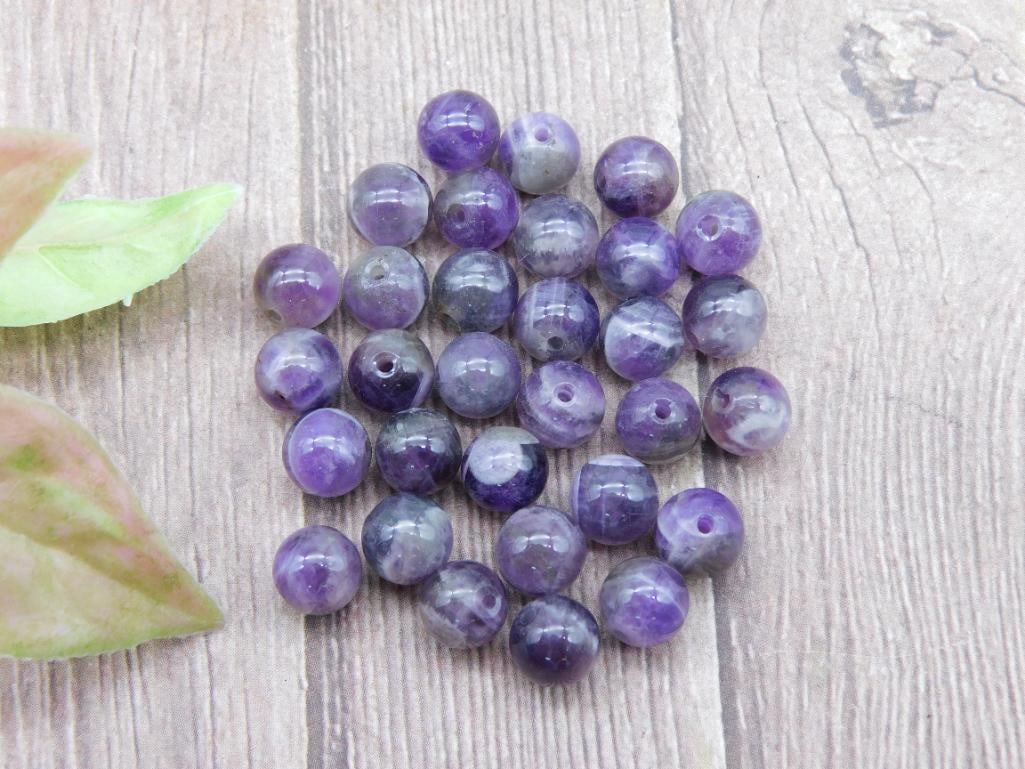 Lot of Purple Amethyst Round Beads for Jewelry Making: This lot includes a collection of round purple amethyst beads, drilled for stringing. The beads display varying shades of purple with natural markings. These are ideal for crafting and jewelry-making 