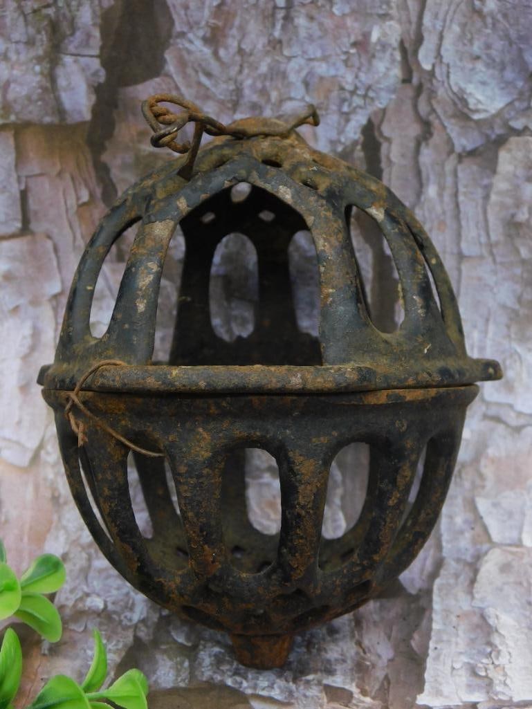 Cast Iron String Holder: This item appears to be a metal, cage-like structure with a slotted design, featuring a weathered, rusted surface. It includes small wire attachments and shows noticeable aging and corrosion. The over