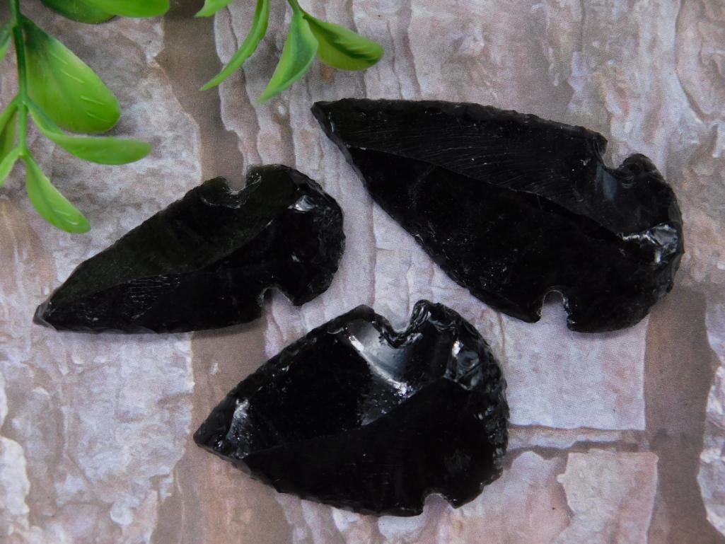 Set of Three Black Obsidian Arrowheads: Set of three handcrafted black obsidian arrowheads with sharp edges. These pieces are ideal for collectors or display. Includes a quarter in one image for size reference. Each arrowhead features natur