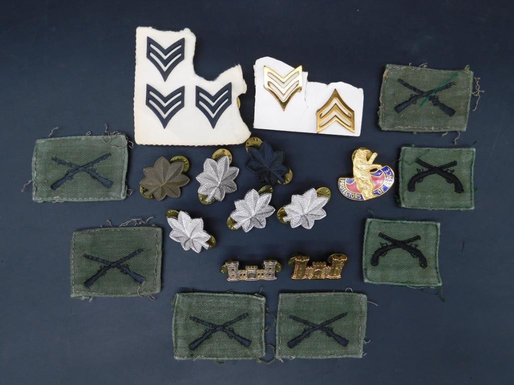 Assorted Military Insignia and Patches Collection: This lot includes a variety of military insignia and patches. Items feature rank chevrons, embroidered crossed rifles on green backgrounds, silver and gold oak leaf insignia, castle pins in gold and s