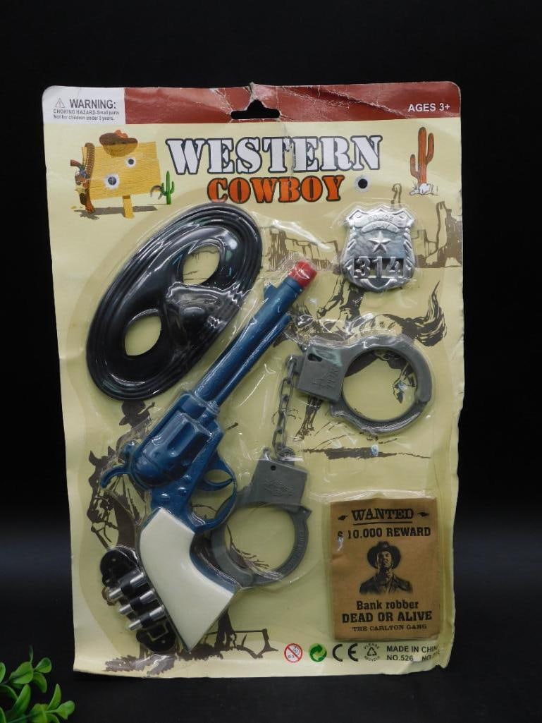 Western Cowboy Toy Set in Original Packaging: Complete Western Cowboy toy set sealed in original packaging. Includes toy revolver, handcuffs, mask, badge, rope, and pouch. Packaging shows 'Western Cowboy' branding and is designed for age 3+ users