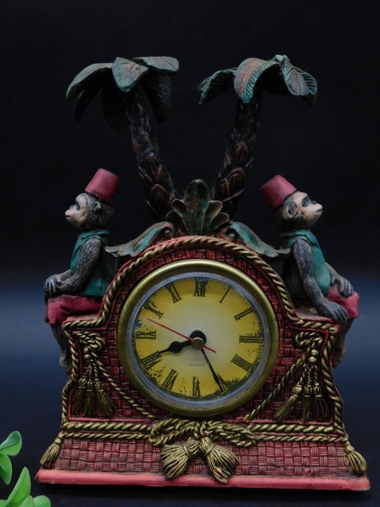 Decorative Quartz Clock With Monkey And Palm Tree Design: This is a decorative quartz clock featuring a colorful design with monkeys and palm trees. The clock face displays Roman numerals and has a red and black hour and minute hand. The back of the clock in