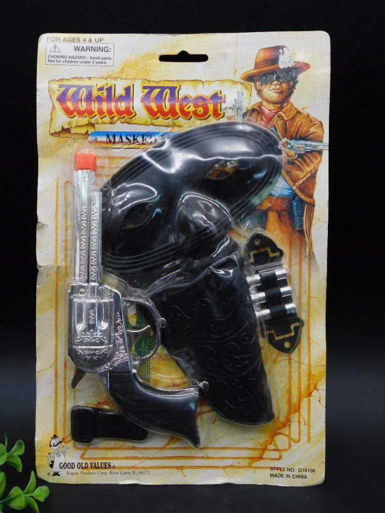 Wild West Toy Gun and Holster Set on Original Card Packaging: Wild West toy gun and holster set, in original card packaging. Includes a plastic revolver with ornately designed holster, belt buckle, and cartridge loop. Set is mounted on a brightly colored backing