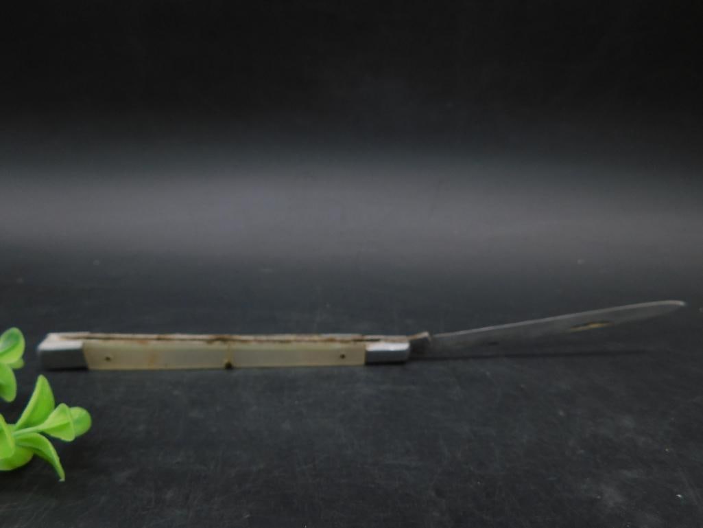 Sabre Japan Long Spear Single Folding Knife: A folding knife marked Sabre Japan. The knife features a narrow, pointed blade and a metal and synthetic handle with visible signs of wear and rusting. Measurements displayed by the ruler suggest comp