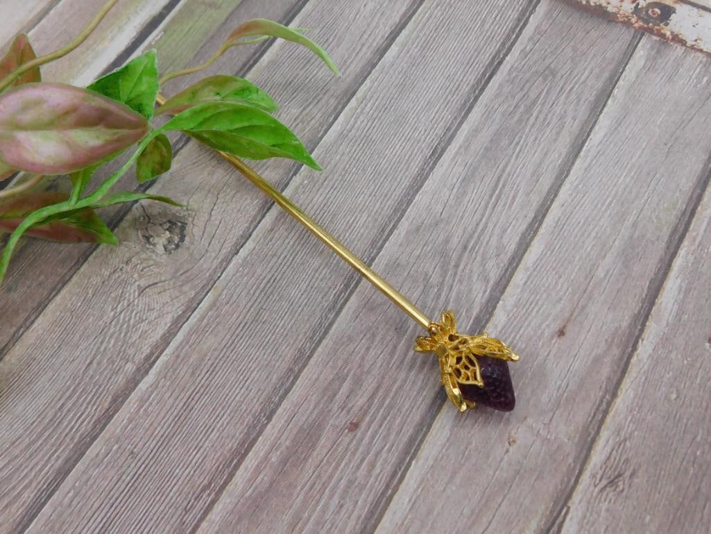 STONE HAIR PIN: Gold-tone stick pin featuring a decorative bee design with a purple stone accent. The pin is approximately 6 inches long and includes intricate detailing on the bee. Condition appears good with no vis