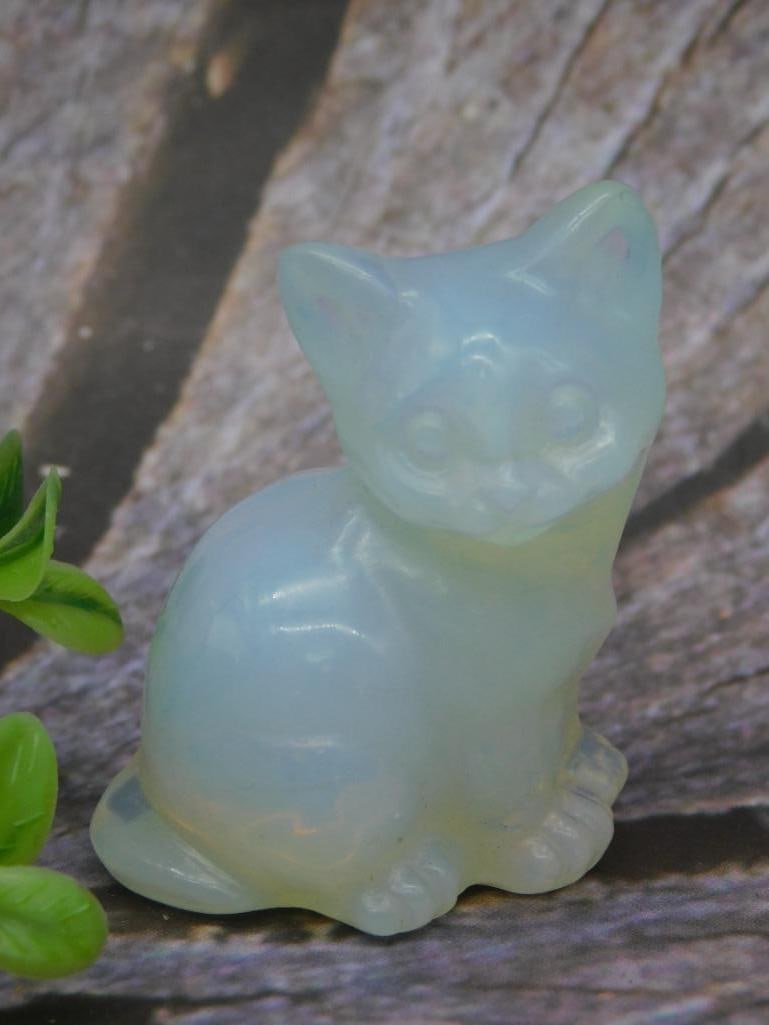 Opalescent Glass Cat Figurine in Sitting Pose Rock Stone Lapidary Specimen: Opalescent glass figurine of a sitting cat with textured details and smooth surface. Approximately a few inches tall. This solid glass piece reflects light and displays a subtle glow, making it a uniq