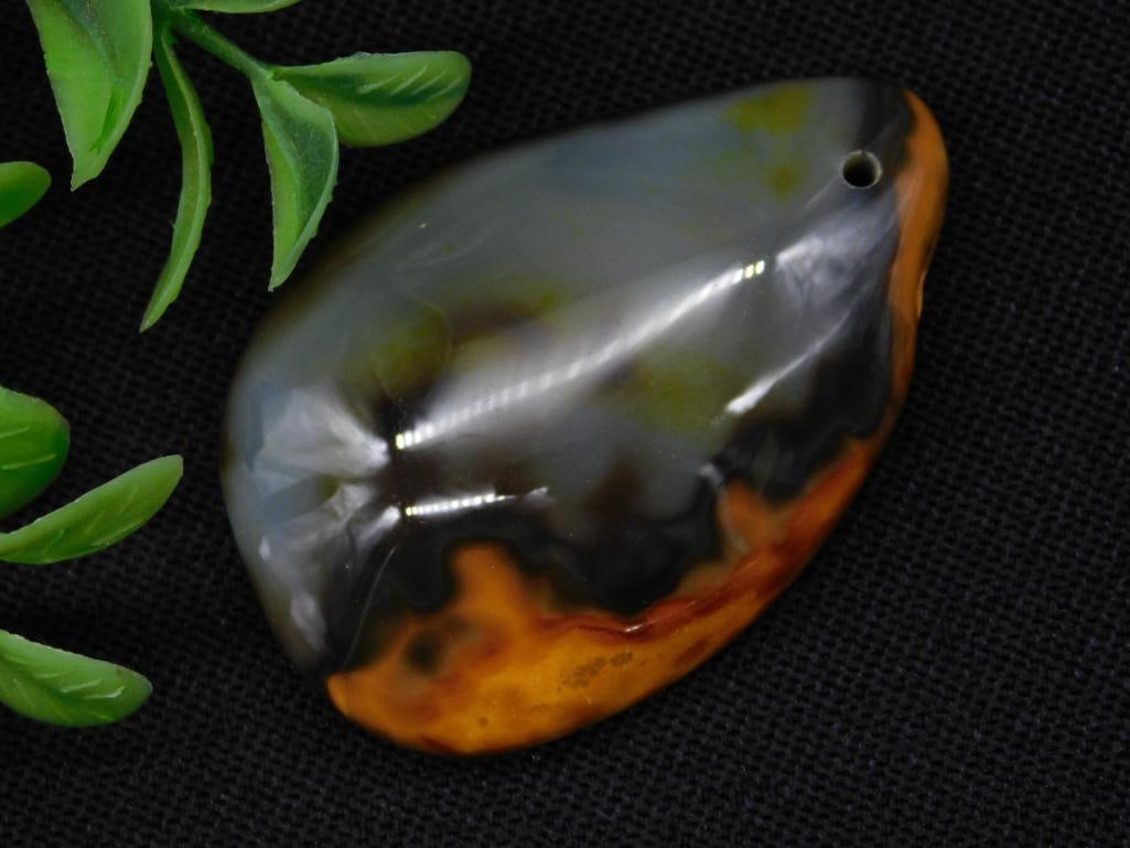 Eclipse Agate Pendant with Drilled Hole Rock Stone Lapidary Specimen: Polished agate pendant featuring unique natural patterns in hues of orange, brown, and gray. Includes a pre-drilled hole for convenient attachment. Approximate size is not specified. Shown with a quar
