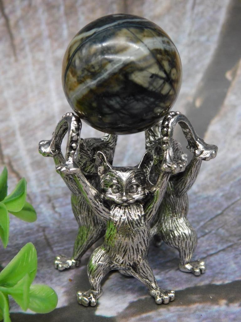 Metal Figurine of Animals Holding a Stone Sphere: A decorative metal figurine featuring three animals holding a polished stone sphere. The metallic base is formed intricately, showing detailed craftsmanship. The stone sphere has an attractive natural