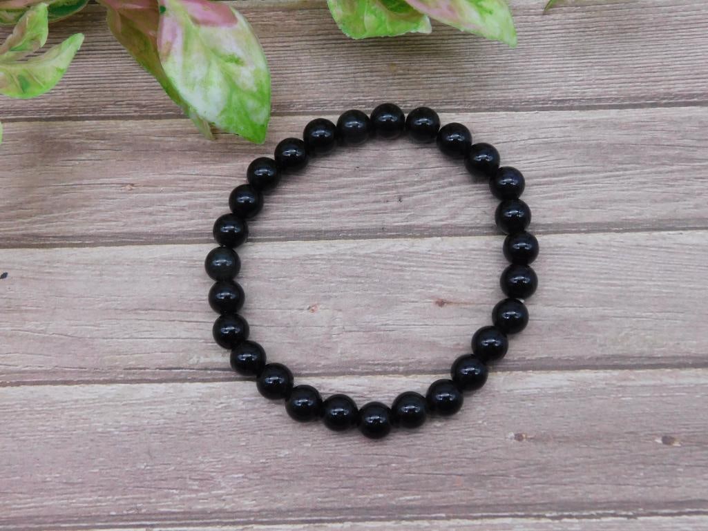 Round Black Beaded Stretch Bracelet: A bracelet featuring round black beads strung on an elastic stretch cord. The beads are uniformly polished and of consistent size. Suitable for various wrist sizes due to its stretchable design. Speci