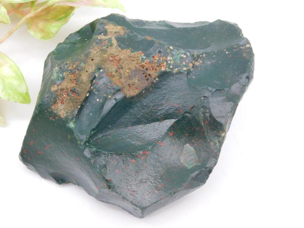 BLOODSTONE ROCK STONE LAPIDARY SPECIMEN: - Natural rough bloodstone specimen. | - Weighs approximately 402 grams. | - Features a deep green hue with lighter inclusions and light reddish-brown spots. | - Unpolished and raw, highlighting its n