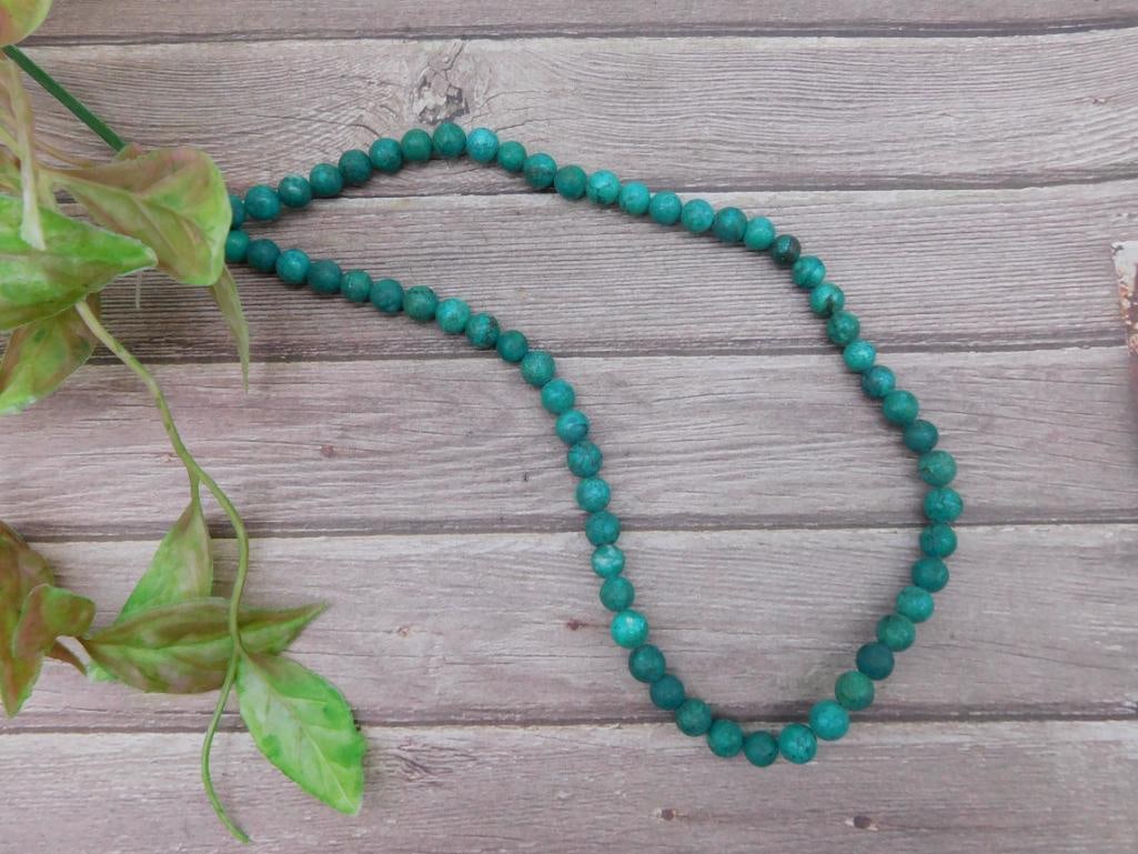 Green Stone Bead Necklace 18-Inch Strand: 18-inch green stone bead necklace featuring round beads. Beads are strung together on a single strand. Suitable for wearing or repurposing for jewelry-making projects. Please note the clasp type is no
