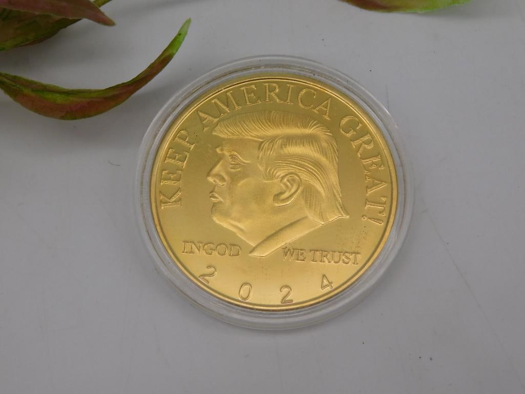 2024 Donald Trump Gold-Tone Commemorative Coin: 2024 gold-tone commemorative coin featuring a profile design on the front with the text 'Keep America Great' and '2024.' Reverse displays a presidential seal design with the text '45th President of th