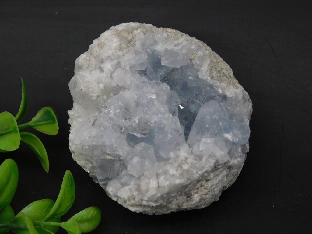 Celestite Geode Cluster Mineral Specimen: - Celestite geode cluster with light blue crystalline formations inside. | - Mineral specimen with a rough exterior and crystalline interior. | - Includes visible quartz-like formations with light-ref