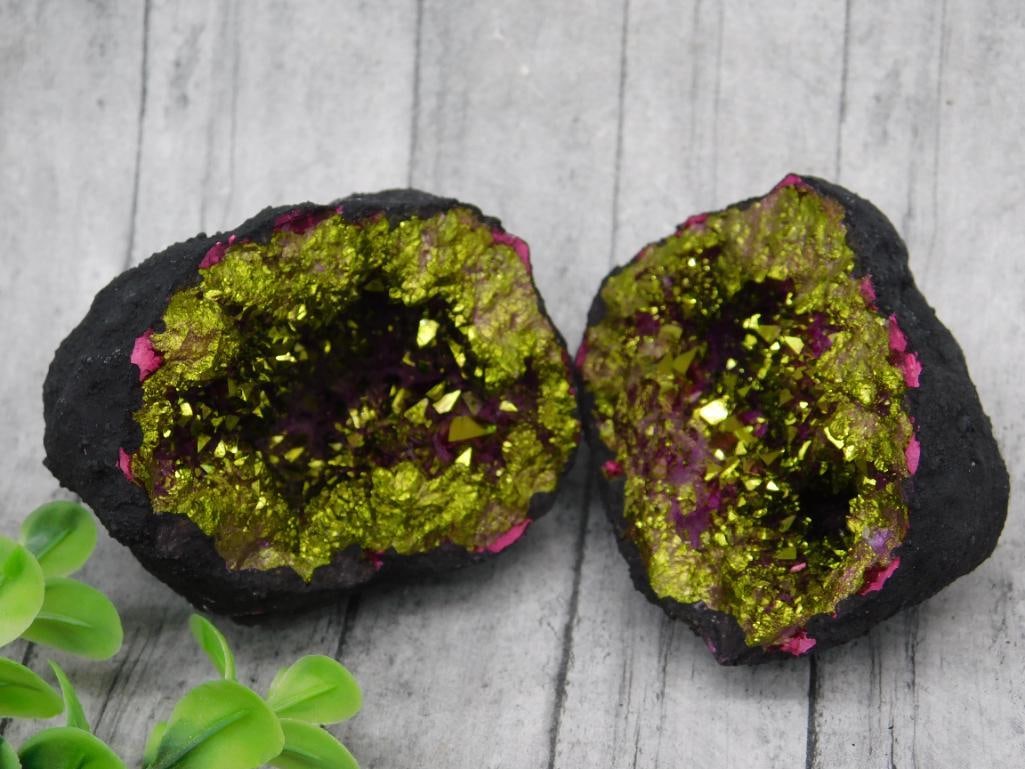 Open Geode with Green and Pink Crystals: This listing features an open geode showcasing vibrant green and pink crystal formations. The geode is split into two pieces, revealing its detailed crystalline interior with reflective surfaces. A co