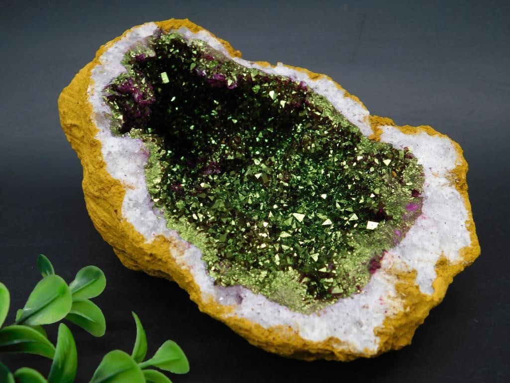 Geode with Green Crystal Interior and Yellow Outer Matrix: A geode featuring a detailed green crystal-lined interior surrounded by a yellow outer matrix. The crystals exhibit natural sparkle, while the outer surface is raw and rugged. Includes a ruler for sca