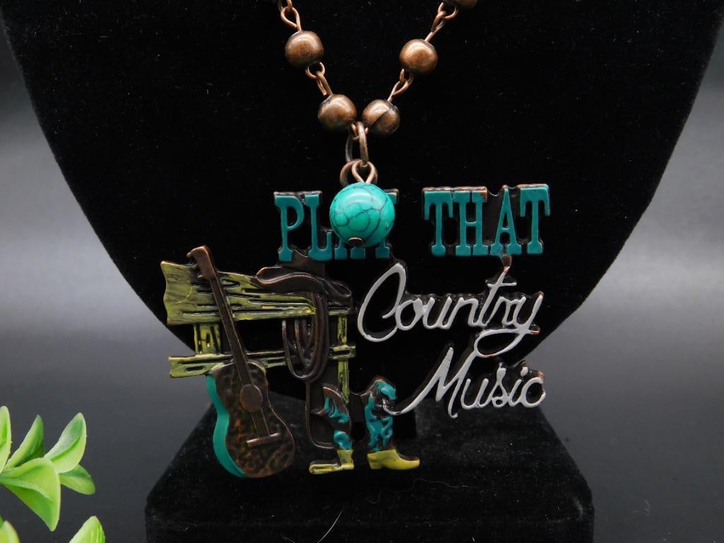 Copper and Turquoise Beaded Necklace With Play That Country Music Pendant: This necklace features a pendant with the phrase 'Play That Country Music' and an accompanying decorative design including a guitar and cowboy boots. The necklace is accented with turquoise beads and