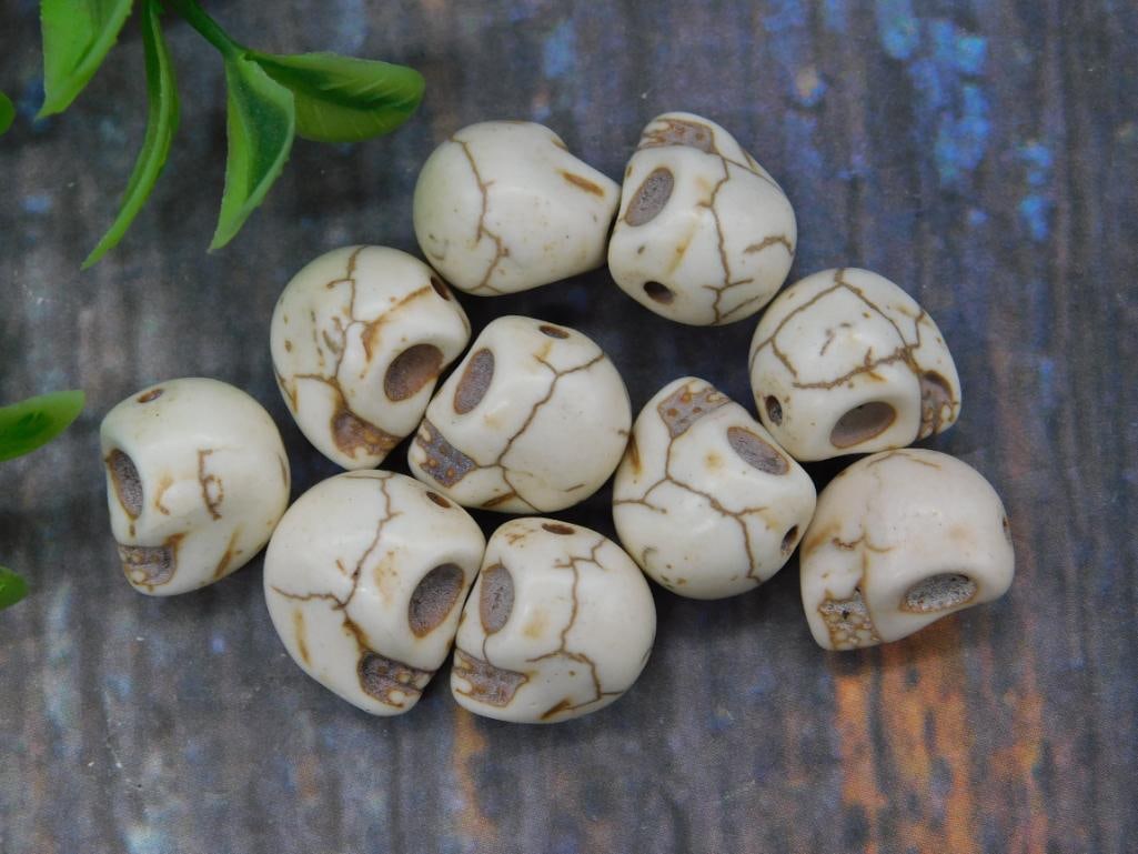 Set of 10 White Skull-Shaped Beads With Vein Pattern: This lot includes 10 skull-shaped beads in a white base tone, featuring a veined pattern finish. Each bead has a central hole for threading, ideal for jewelry or craft-making purposes. These beads are
