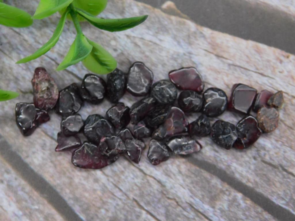 Loose Red Garnet Gemstones for Jewelry or Collection: A lot of loose red garnet stones with a deep reddish hue. Includes a variety of raw, unpolished pieces with natural irregular shapes and sizes. Approximate size and weight information not specified. I