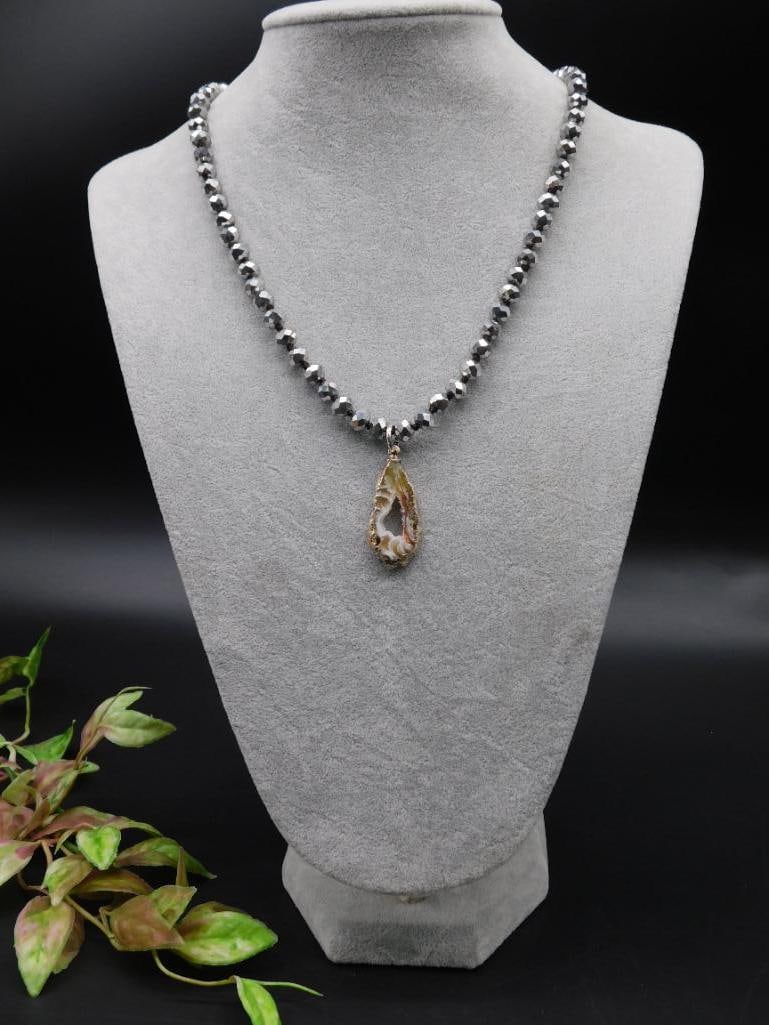 Faceted Beaded Necklace with Open Agate Pendant: This necklace features faceted beads and showcases a natural open agate slice pendant. The pendant has a unique natural design and is framed in a metallic finish. The necklace has an overall simple ye