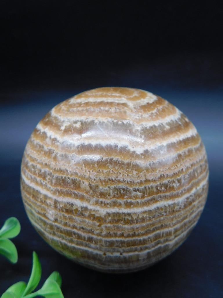 Brown Onyx Sphere Decorative Object: Brown onyx sphere with natural striations. Approximate weight is 1 lb 12 oz (812 g). Measures approximately 3 inches in diameter, as indicated next to a ruler. Ideal for display or collection purposes