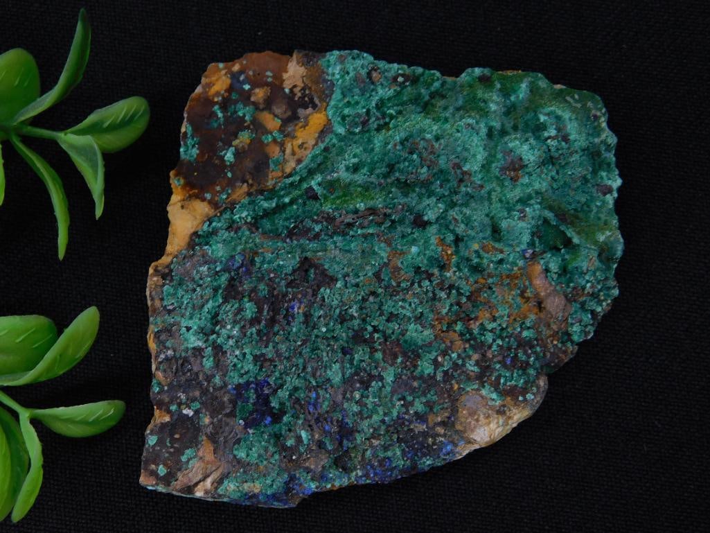 Malachite Specimen with Green and Blue Crystals: A mineral specimen featuring vibrant green and blue crystallization across its surface. The piece is irregularly shaped and includes earthy tones in addition to the vibrant colors. Comes with auction