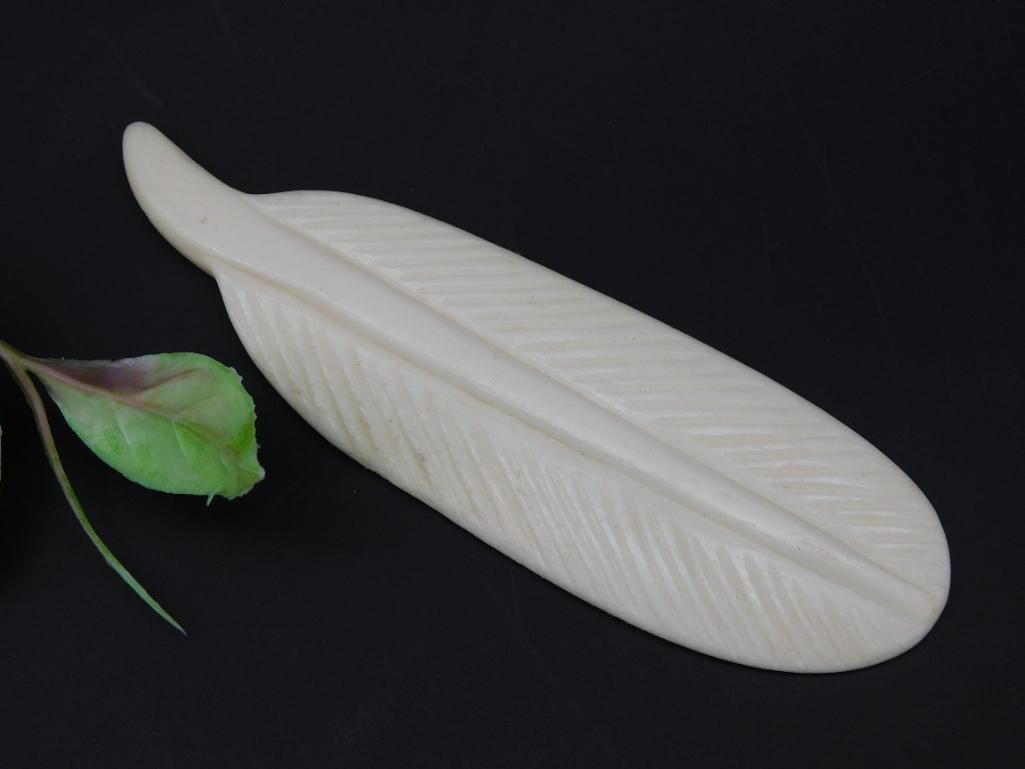 Carved Bone Feather Decorative Object: A carved bone feather featuring detailed linear textures for a realistic appearance. Approximately 5 inches long, as shown against a measurement scale. A small and lightweight decorative object ideal