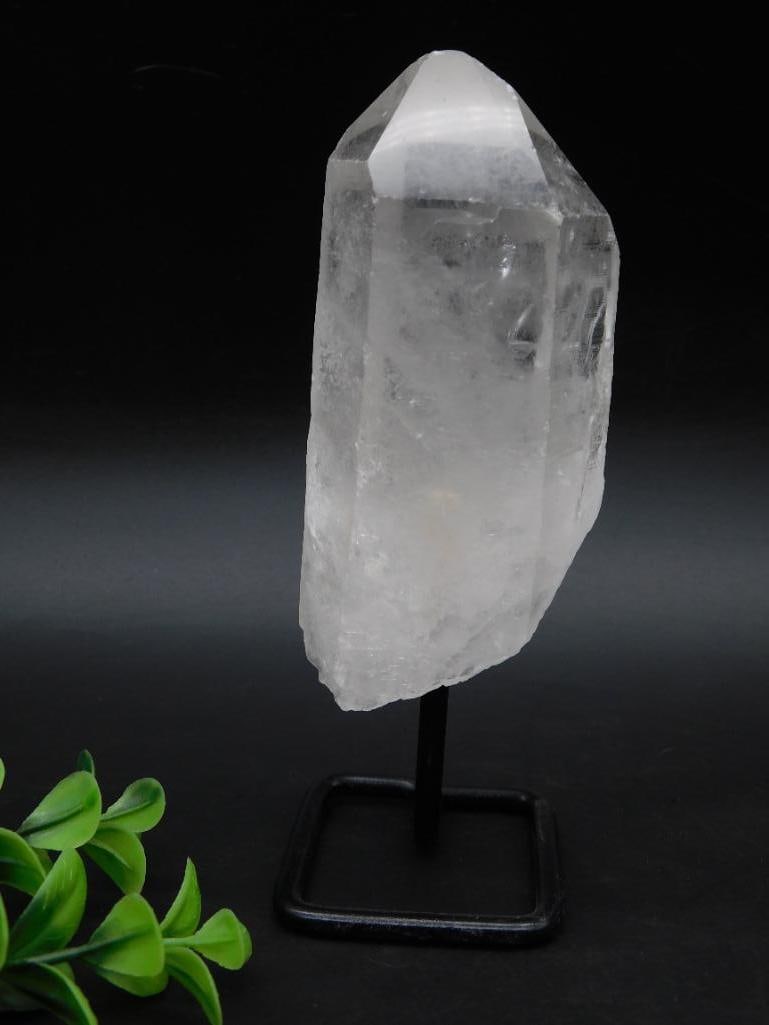 Quartz Crystal Point With Metal Stand: Quartz crystal point displayed on a black metal stand. The material is translucent and features natural inclusions and clarity variations characteristic of quartz. Includes ruler for scale in the list
