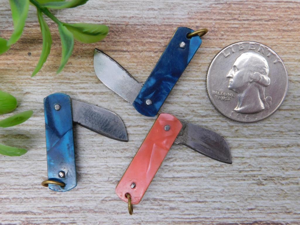 Set of Three Miniature Pocket Knives: Set of three miniature folding pocket knives, featuring varied colorful handles including blue and orange. Each knife includes a small loop for attachment to keychains or other accessories. The blades