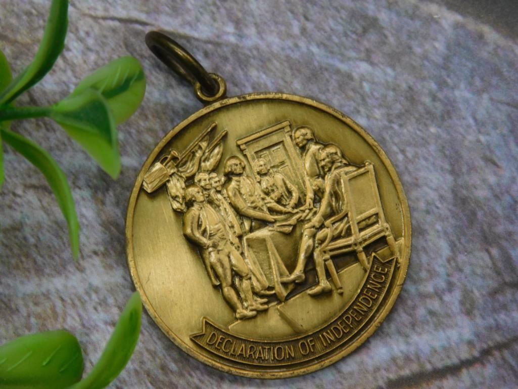 United States Bicentennial Medal With Declaration of Independence Design: Gold-tone medal featuring the Declaration of Independence design on one side and 'United States of America 1776-1976' with Liberty Bell on the other. Includes attached loop for hanging or display. App