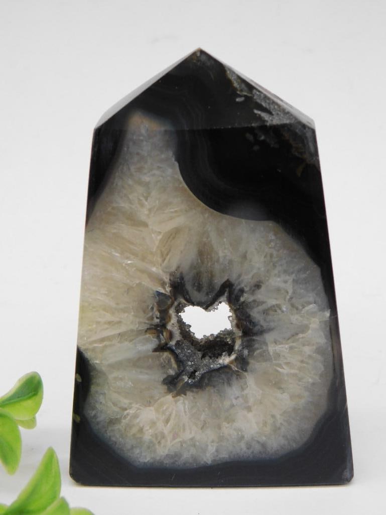 Polished Agate Crystal Point With Geode Center ROCK STONE LAPIDARY SPECIMEN: Polished agate crystal point showcasing a stunning geode center with a natural cavity. Features contrasting black and white banded patterns with a prominent central crystal formation. Weighs approxima