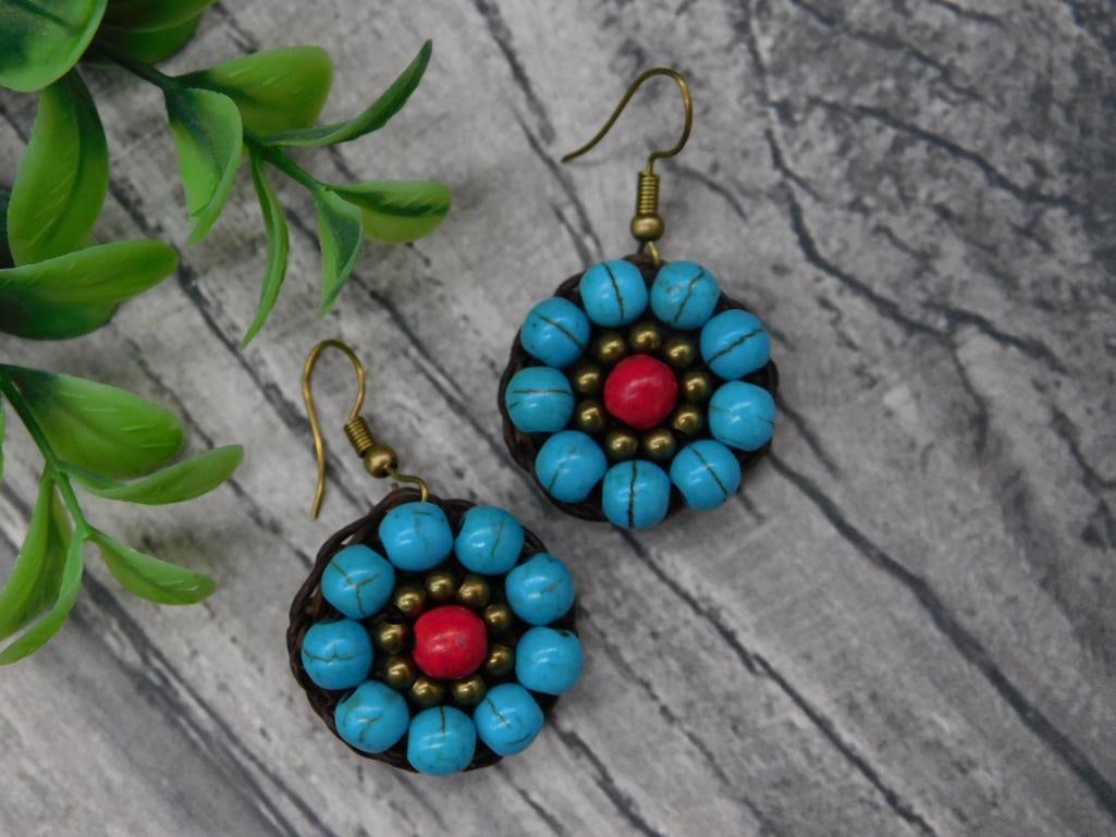 Turquoise and Red Beaded Earrings With Brass Hooks: A pair of handcrafted earrings featuring turquoise-colored beads arranged in a circular pattern with a central red bead, accented by small brass-colored spacer beads. The earrings are fitted with bras