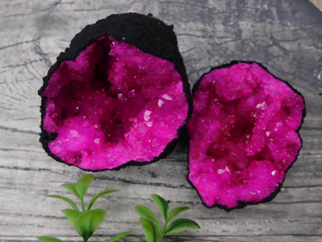 Bright Pink Quartz Geode Rock Stone Lapidary Specimen: This vibrant pink quartz geode features a striking crystalline interior with a black exterior. Presented as two halves, it is a visually impressive specimen. The geode weighs approximately 254 grams,
