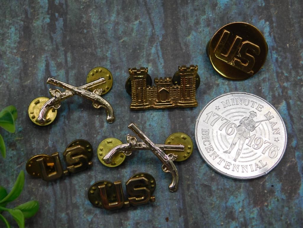 Set of U.S. Military Collar Pins with Castle and Crossed Pistols: This lot includes a set of U.S. military collar pins featuring designs such as 'US,' castle insignia, and crossed pistols. Pins come with backings that secure them in place and bear markings such as '