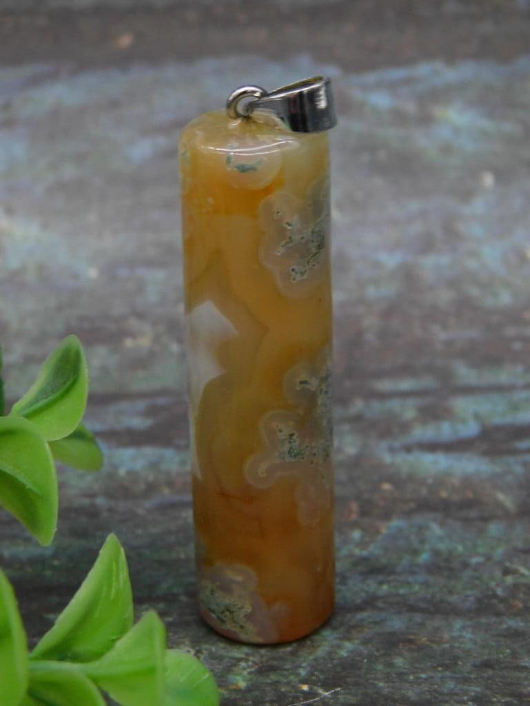 Agate Pendant with Cylindrical Design Rock Stone Lapidary Specimen: Cylindrical pendant made of agate, showcasing natural patterns and earthy tones. Features a small metal cap with a hoop for attachment to chains or cords. Suitable for jewelry making or personal adorn