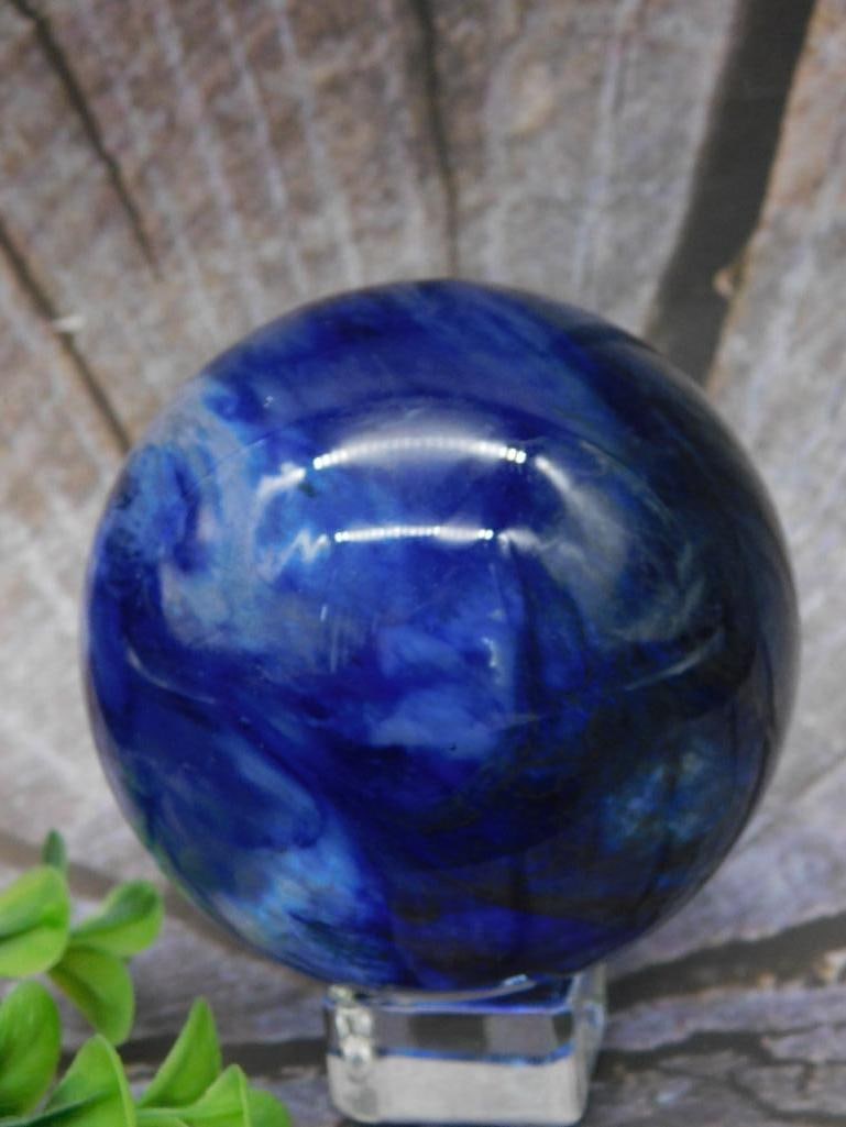 Polished Blue Stone Sphere Rock Stone Lapidary Specimen: A polished blue stone sphere featuring captivating swirls of color. The sphere comes with a clear stand for display. The listed weight is 2 grams, and it is identified as Lot 708815 from the 2025 Rock